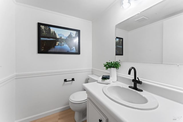 bathroom featuring toilet, ornamental molding, wood-type flooring, and vanity