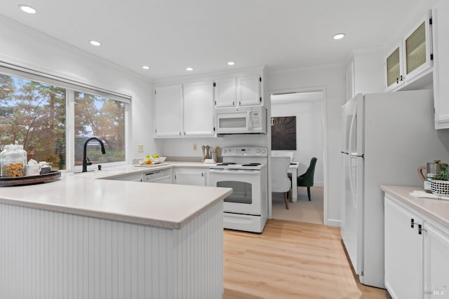 kitchen with white appliances, white cabinetry, sink, ornamental molding, and light wood-type flooring