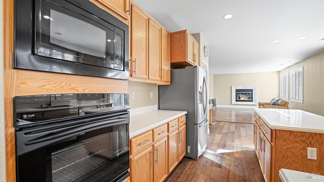 kitchen with a kitchen island, dark hardwood / wood-style flooring, and black appliances