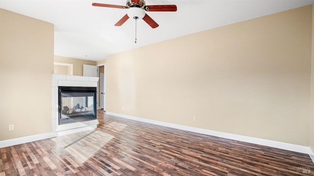 unfurnished living room with a multi sided fireplace, dark wood-type flooring, and ceiling fan