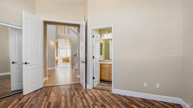 unfurnished bedroom featuring ensuite bathroom, sink, dark hardwood / wood-style flooring, and a closet