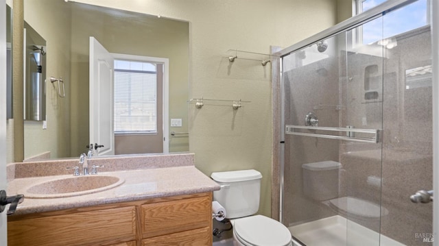 bathroom with vanity, a healthy amount of sunlight, walk in shower, and toilet