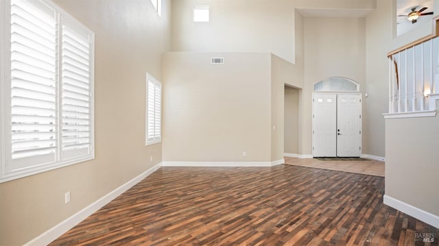 foyer featuring ceiling fan, a healthy amount of sunlight, dark hardwood / wood-style flooring, and a high ceiling