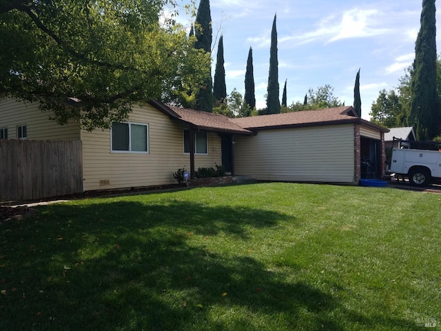 single story home featuring an attached garage, a front lawn, and fence