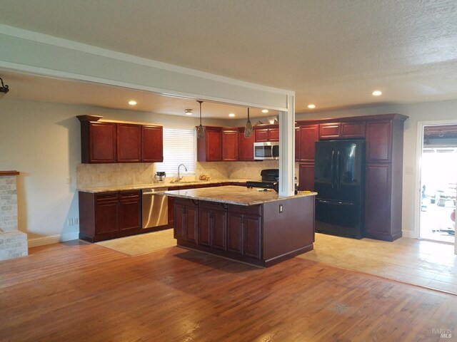 kitchen featuring sink, light hardwood / wood-style flooring, a kitchen island, and black appliances