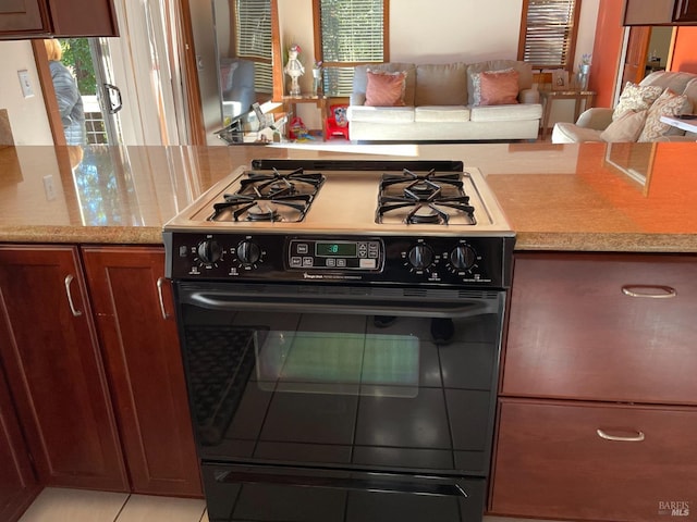 kitchen featuring gas stove, light stone countertops, and light tile patterned flooring