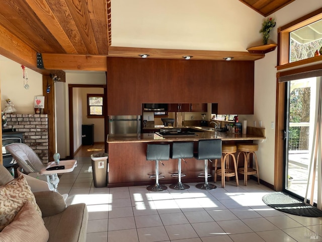 kitchen featuring kitchen peninsula, light tile patterned floors, wood ceiling, a breakfast bar area, and stainless steel refrigerator