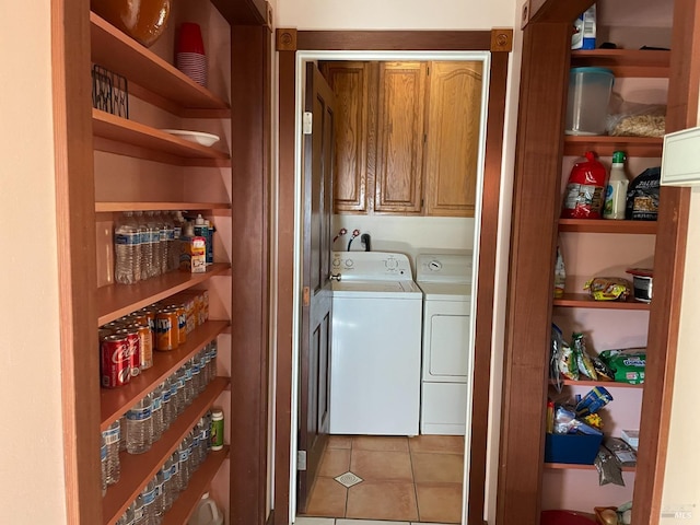 washroom with washer and clothes dryer, cabinets, and light tile patterned floors