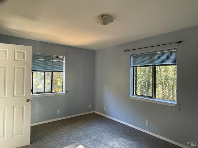 empty room with dark carpet and plenty of natural light