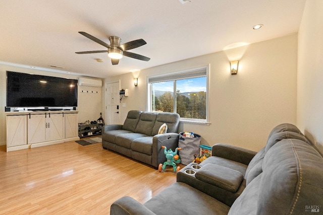 living room featuring hardwood / wood-style flooring, ceiling fan, and a wall unit AC