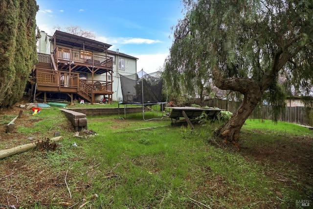 view of yard featuring a trampoline and a wooden deck