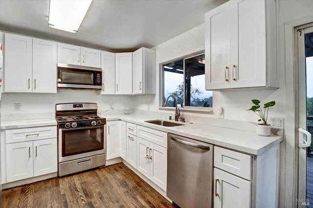 kitchen with white cabinets, sink, dark hardwood / wood-style floors, light stone counters, and stainless steel appliances