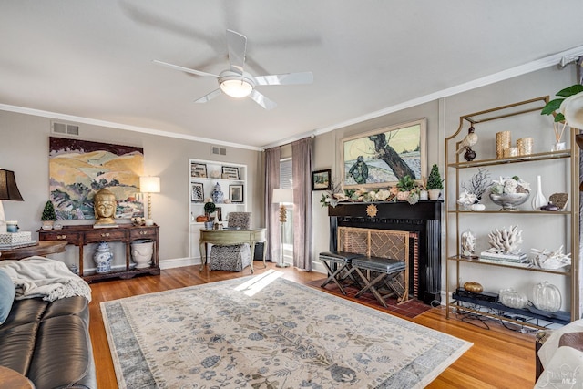 living room with a fireplace with flush hearth, visible vents, and ornamental molding