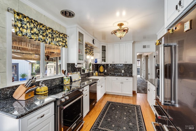 kitchen featuring electric range, visible vents, glass insert cabinets, dark stone countertops, and white cabinetry