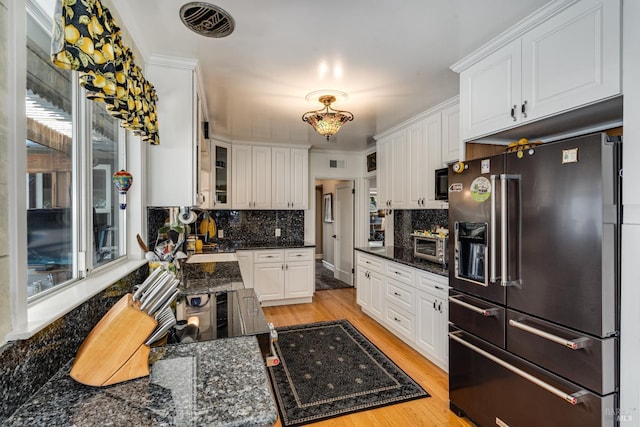 kitchen with glass insert cabinets, high end fridge, white cabinetry, and dark stone counters