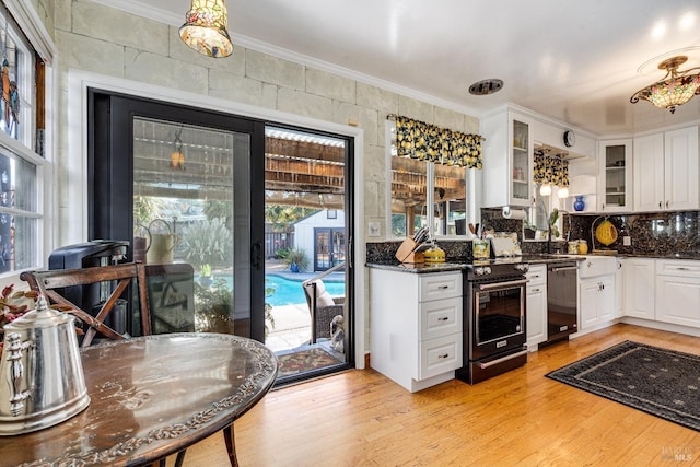 kitchen with white cabinets, light wood-style floors, glass insert cabinets, dark stone countertops, and black appliances