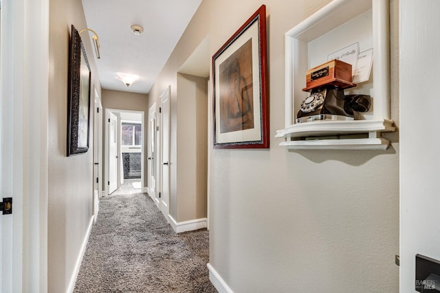 hallway featuring carpet and baseboards