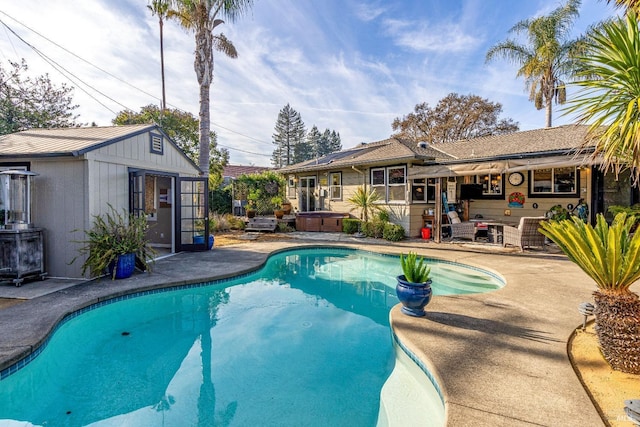 outdoor pool with a patio, a hot tub, and an outdoor structure