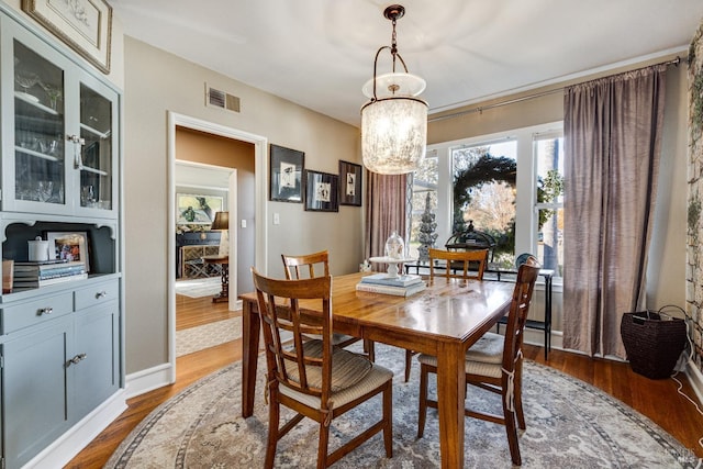 dining area featuring dark wood-style flooring, visible vents, and an inviting chandelier