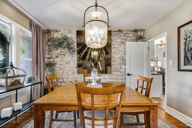 dining area with baseboards, a chandelier, and wood finished floors