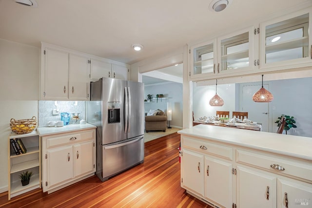 kitchen featuring stainless steel fridge, white cabinets, decorative light fixtures, and light wood-type flooring