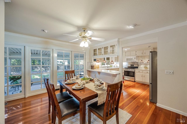 dining room featuring light wood-type flooring, a wealth of natural light, and crown molding