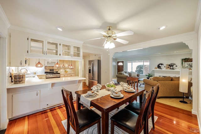 dining space featuring light hardwood / wood-style flooring, ceiling fan, ornamental molding, and sink