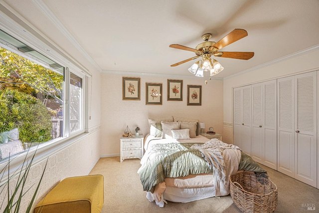 carpeted bedroom with ceiling fan, ornamental molding, and a closet