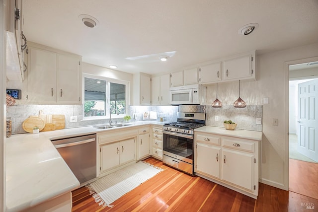 kitchen with backsplash, light hardwood / wood-style floors, sink, and appliances with stainless steel finishes