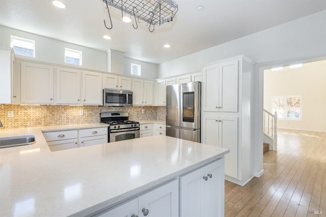 kitchen with sink, white cabinets, stainless steel appliances, and light wood-type flooring