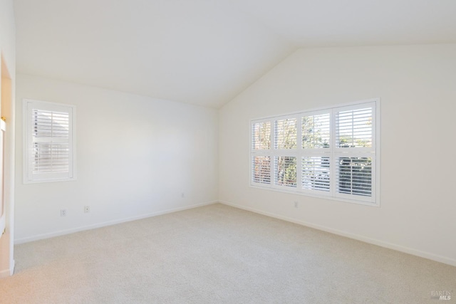 unfurnished room featuring light carpet and vaulted ceiling