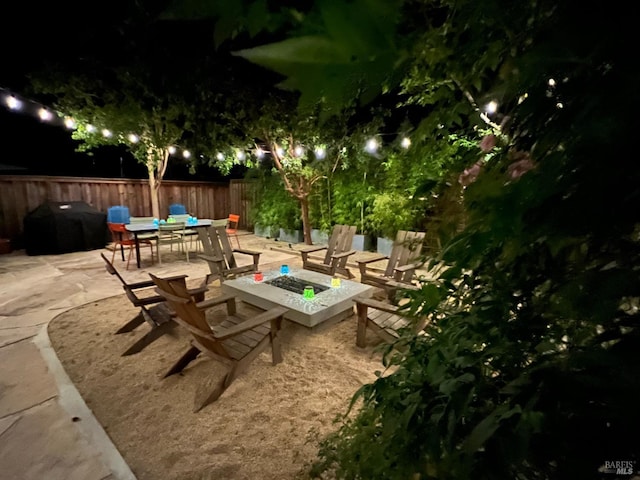 patio at night featuring an outdoor fire pit and grilling area