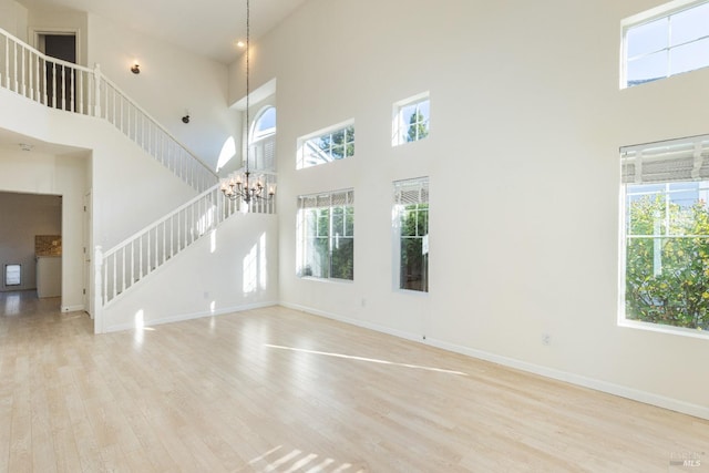 unfurnished living room with basketball hoop, a towering ceiling, and a healthy amount of sunlight