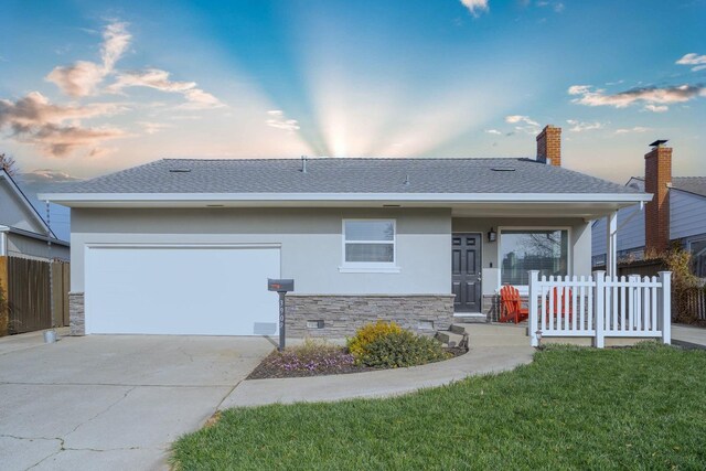 ranch-style home featuring a garage, a yard, and covered porch