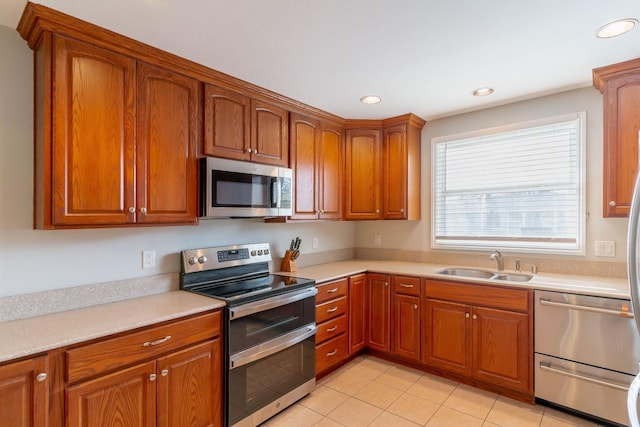 kitchen with appliances with stainless steel finishes, sink, and light tile patterned floors