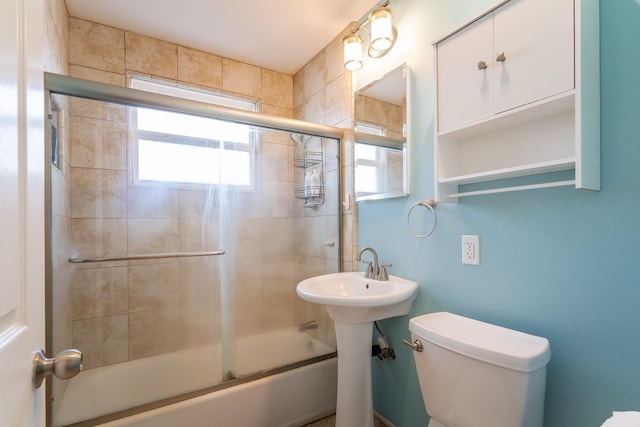 bathroom featuring plenty of natural light, toilet, and combined bath / shower with glass door