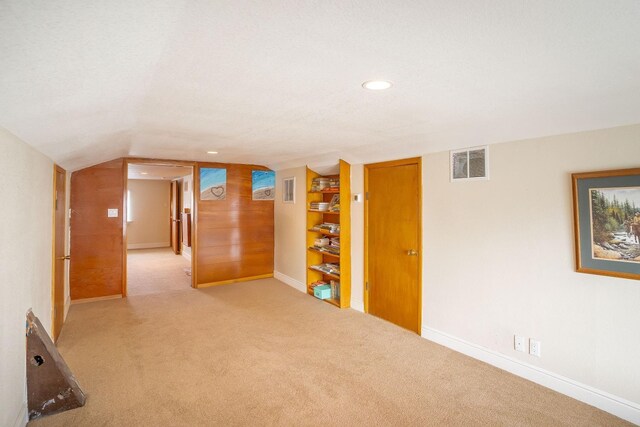 empty room with light carpet, lofted ceiling, and a textured ceiling