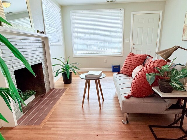 living room featuring a brick fireplace and light hardwood / wood-style flooring