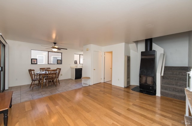 living room featuring ceiling fan, a wood stove, and light wood-type flooring