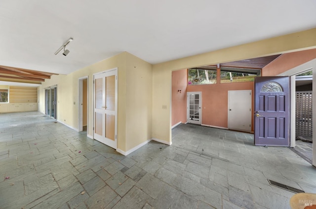 unfurnished room featuring vaulted ceiling with beams