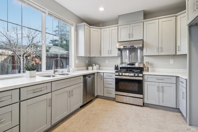 kitchen featuring gray cabinetry, sink, stainless steel appliances, and exhaust hood