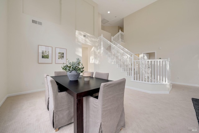 dining area featuring visible vents, light carpet, baseboards, and stairs