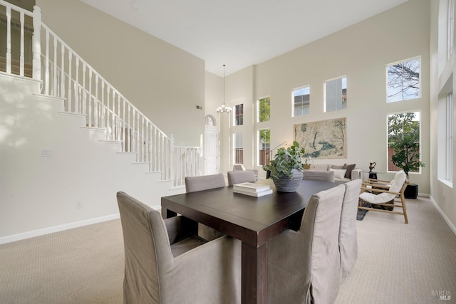 dining room featuring light carpet, a towering ceiling, baseboards, stairs, and an inviting chandelier