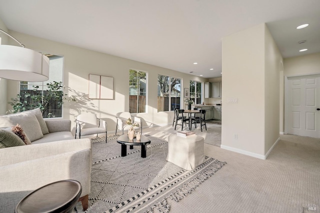 living area with recessed lighting, light carpet, and baseboards