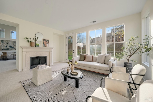 living room featuring light colored carpet, a fireplace, visible vents, and baseboards