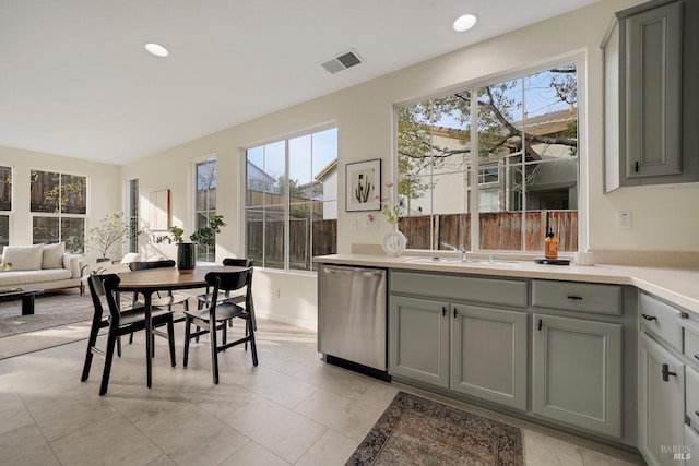 kitchen featuring a sink, plenty of natural light, light countertops, and stainless steel dishwasher