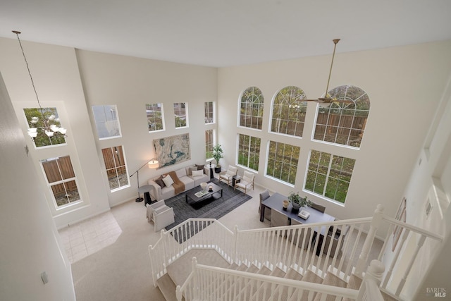 living room with light colored carpet, a notable chandelier, and a high ceiling