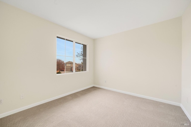 carpeted spare room featuring baseboards