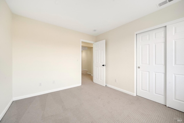 unfurnished bedroom featuring light carpet, baseboards, visible vents, and a closet