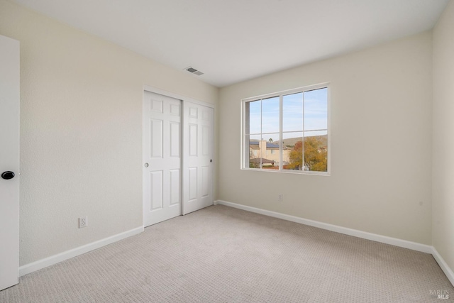 unfurnished bedroom with carpet, a closet, visible vents, and baseboards